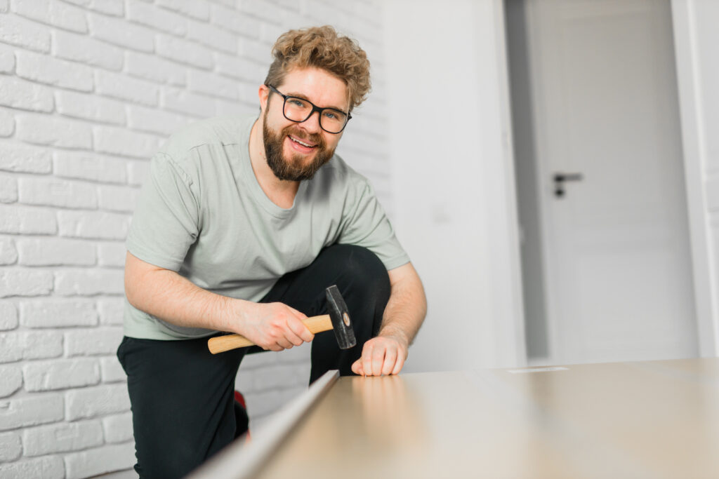 Young attractive man assembles furniture - handwerker and interior objects concept